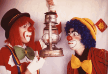 two clowns are standing next to each other and one is holding a lamp