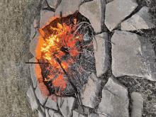 a fire pit surrounded by rocks and grass with a stick sticking out of it