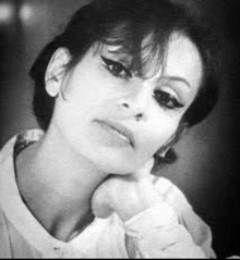 a black and white photo of a woman holding her hand to her chin .