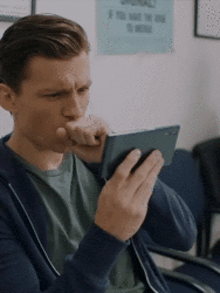 a man is sitting in a chair looking at his phone .