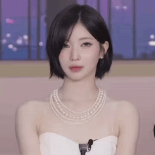 a woman wearing a white dress and a pearl necklace .