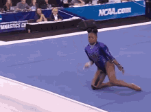 a woman in a purple leotard is doing a trick on the floor in front of a sign that says ncaa.com