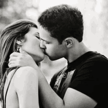 a man and a woman kissing in a black and white photo .