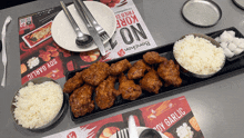 a plate of fried chicken and rice sits on a table