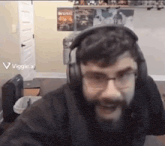 a man with a beard and glasses is wearing headphones and smiling .