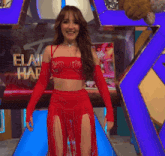 a woman in a red dress is smiling in front of a sign that says elay har