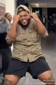 a man in a camouflage shirt is dancing in a hallway .