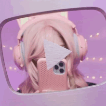 a girl wearing pink headphones is taking a selfie in a mirror .