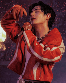 a man in a red jacket is holding a microphone