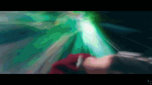 a blurry image of a person holding a sword with a green light behind them
