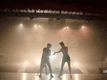 a man and a woman are dancing on a stage in front of a disney sign