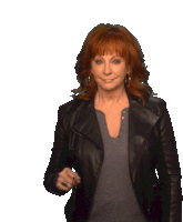 a woman with red hair wearing a black leather jacket and a grey shirt