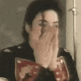 a close up of a man covering his mouth with his hands .