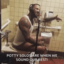a man is sitting on a toilet singing into a microphone .