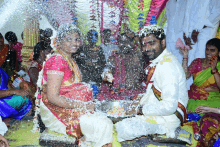 a bride and groom are sitting in front of a crowd with flowers on their heads