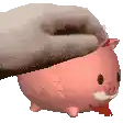 a person is petting a pink piggy bank with a red bow .