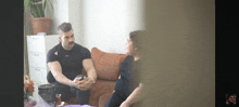 a man and a woman sit on a couch having a conversation