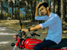 a man sits on a red honda motorcycle