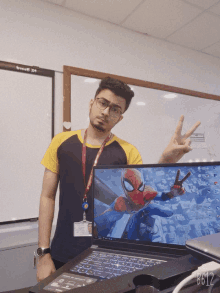 a man giving a peace sign next to a laptop