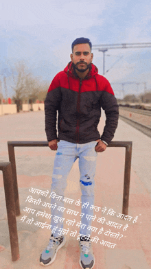 a man in a red and black jacket stands next to a rail