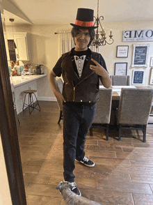 a man in a top hat takes a selfie in front of a mirror with a sign on the wall that says home