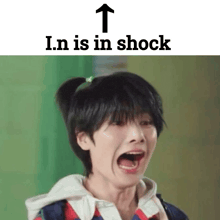 a young boy with a ponytail is making a funny face with his mouth open and the words `` in is in shock '' above him