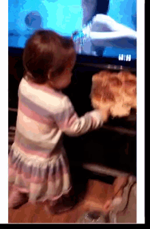 a little girl is reaching for a piece of bread in front of a tv screen that says ' going ' on it