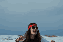 a woman wearing sunglasses and a red bandana is standing in the snow