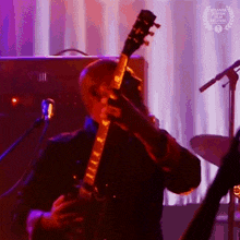 a man is playing a guitar in front of a microphone and a laurel wreath that says atlanta international film festival on it