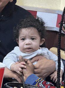 a baby with curly hair is being held by someone