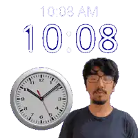 a man wearing glasses stands next to a clock that says 10:08 am
