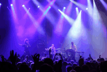 a band on stage with purple lights behind them