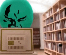 a green ball with a face on it sits on top of a laptop