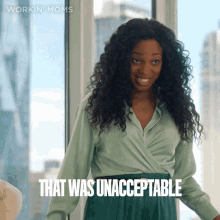 a woman in a green shirt says that was unacceptable in front of a window