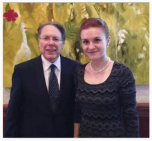 a man in a suit and tie is posing for a picture with a woman in a dress .