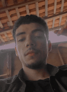 a young man with a beard and a black shirt looks at the camera