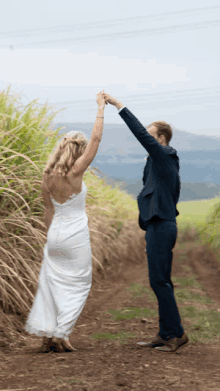 a bride and groom are dancing in a field