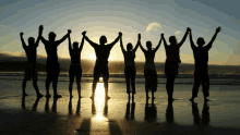 a group of people standing on the beach holding hands