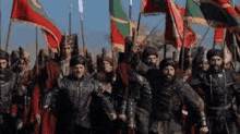 a large group of soldiers are marching in a line holding flags .