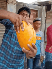 a man in a plaid shirt is holding a large yellow ball and a boy in a blue shirt with the word inal on it