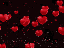 a bunch of red hearts are falling on a black background .