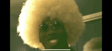 a man wearing sunglasses and an afro wig is smiling