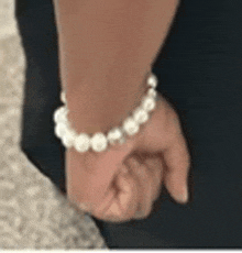 a woman wearing a pearl bracelet on her wrist .