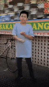 a boy in a blue shirt is standing in front of a food stand with a bicycle in front of it