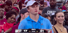 a man in a blue shirt with the letter a on it watches a game