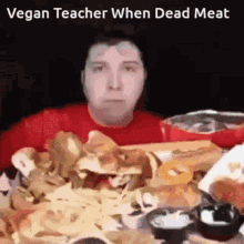 a man is sitting at a table with a bunch of food and a caption that says vegan teacher when dead meat