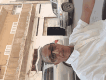 a man wearing glasses is standing in front of a car