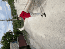 a man in a red hoodie stands on a dirt road