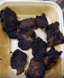 a styrofoam container filled with pieces of burnt food