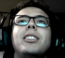 a man wearing headphones and glasses looks up at the camera